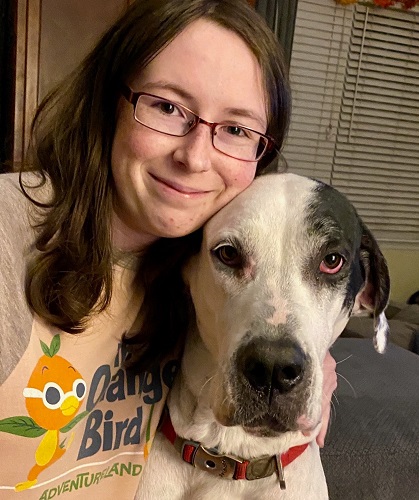 Emma sitting next to a large, white Great Dane dog