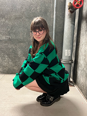 Cami Dressed In A Black And Green Checkered Cardigan While Squatting In A Stairway